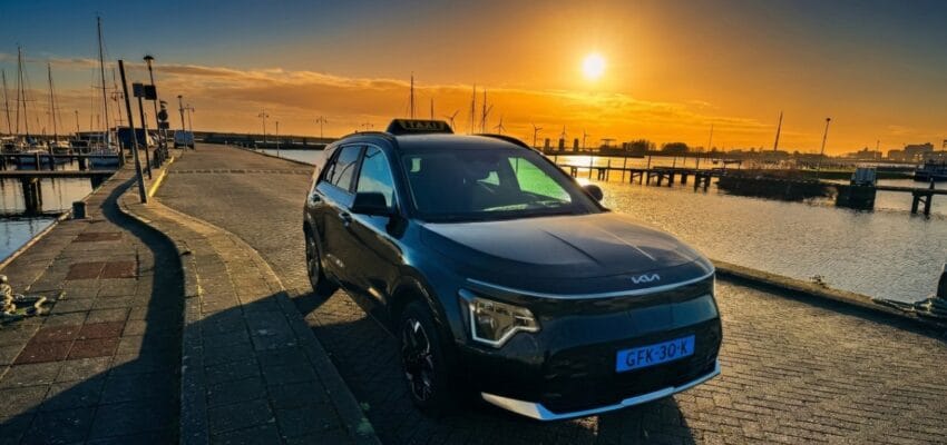 Een zwarte elektrische Kia Niro EV van Den Taxi bij de haven van Enkhuizen.